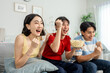 © Kawee - Diverse Asian young friends watching football sport game on television.