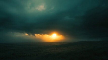 A dramatic sky with a bright sun peaking through dark clouds over a hazy landscape horizon view