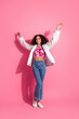© deagreez - Stylish young woman with curly hair posing in casual fashion against a pink vertical background