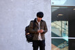 © Austockphoto - Young Chinese university student standing using mobile phone and wireless headphones