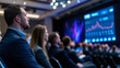 © Maksym - Rear shot of an international conference, audience members from various industries listening intently as the speaker presents financial projections on large screens flanking the st