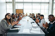 © Jacob Lund - First-person view of people clapping at a business meeting around a long table