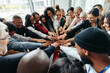© Jacob Lund - Corporate team with hands united celebrating success and teamwork in modern office environment