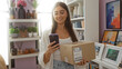 © Krakenimages.com - Woman holding phone and package in decorated home with plants and pictures around
