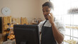 © Krakenimages.com - Young man working in bakery while talking on phone, surrounded by bread and pastries