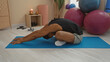 © Krakenimages.com - Young man stretching on a blue yoga mat in a gym with candles, dumbbells, and exercise balls in the background