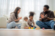 © Hip.hub - Family plays together on a soft rug in a bright living room while a baby explores colorful blocks with siblings