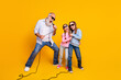 © deagreez - Elderly man with two young girls singing karaoke against vibrant yellow backdrop showcasing bonding and fun moments