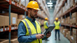 © EPICreation - Potrait of man wearing safety helmet and vest with holding tablet while inspecting warehouse, boxes and other workers background, warehouse management or logistics environment