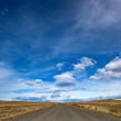 © Tetra Images - Clouds over empty road in grassy landscape