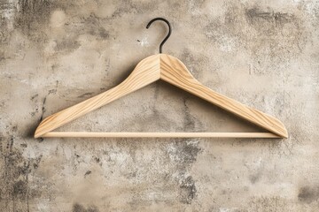 Leinwandbilder - Wooden hanger against a textured wall in a minimalist setting for organizing or displaying clothing items