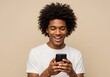 © Aklima - A smiling man with curly hair using a smartphone against a neutral colored studio backdrop scene is shown