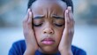 © Olena - Young African American Boy Experiencing Discomfort While Touching His Temples, Capturing Anxiety and Confusion