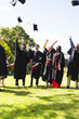 © Wavebreak Media - Graduating diverse students tossing caps in air, celebrating in garden with joy, copy space