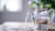 © SATRIANANGISAN - Silver teapot pouring water onto a light wooden surface