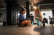© DusanJelicic - Personal trainer stretching legs and assisting an overweight woman during a workout session in a gym, promoting healthy lifestyle and fitness