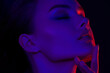 © Mirrorstudio - Young caucasian female in neon lighting with eyes closed and hand on chin