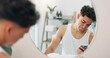 © WestLey/peopleimages.com - Mirror, skincare and man with smartphone, morning and internet with social media, cyberbullying and acne. Person, reflection and guy in bathroom, cellphone and online reading for cosmetic advice