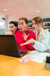 © Jose Calsina - Three surprised girls engaged in an exciting moment while using a laptop together in a library, their expressions filled with wonder and curiosity as they discover something intriguing on the screen