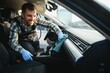 © Serhii - Car detailing and car wash concept. Young man, car wash worker, wearing protective rubber gloves, cleaning interior of the car