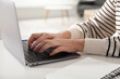 © New Africa - Woman learning online using laptop at white table indoors, closeup. Self-study