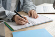 © New Africa - Woman taking notes at wooden table indoors, closeup. Self-study