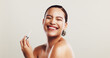 © KayExam/peopleimages.com - Smile, woman and serum for skincare in studio of facial treatment, collagen benefits and dermatology. Person, laughing and oil product for self care, hyaluronic acid and hydration on white background