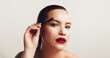 © KayExam/peopleimages.com - Beauty, girl or brush eyebrow in studio for makeup application, face transformation or portrait. Space, woman or mascara tool for facial hair shape, cosmetics or self care routine on white background