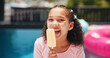 © Flashizzle/peopleimages.com - Happy girl, portrait or pool with popsicle for summer treat, holiday or vacation at luxury resort. Female person, child or kid eating with smile, dessert or ice cream for sweet or cold snack at house