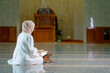 © maya1313 - Ramadan, quran, The image of an Asian Muslim woman in the Islamic religion in hijab in cream color. reading the Quran and having a happy Staying in a beautiful mosque, Arabic word Holy Al Quran.