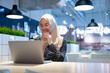 © maya1313 - Cheerful muslim lady in hijab working online at cafe, using laptop, copy space. Side view of smiling arab woman freelancer typing on laptop, enjoying her distant job, Muslim working woman concept.