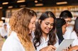 © Rawpixel.com - Group of diverse young adults in a library, girls smiling and using a tablet. They are engaged, happy, and focused on technology and learning together. Diverse girls working together in school.