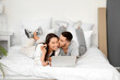 © Pixel-Shot - Young couple with keys and laptop video chatting in bedroom on moving day