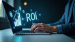 © Netaya - Hand typing on laptop with holographic ROI graph and financial strategy icons representing analyzing ROI and business strategy in empty space concept as Hand types on laptop displaying holographic ROI