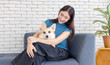 © Bangkok Click Studio - Portrait of asian young beautiful woman happy smile hugging puppy cute welsh corgi dog sitting on sofa playing funny animals in living room, concept embracing lifestyle enjoying trust love pet friend.