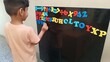 © Mrudang - An Indian boy from village is engaged in learning with colorful magnetic letters and numbers on a blackboard, fostering early education, creativity, and cognitive development in a playful environment