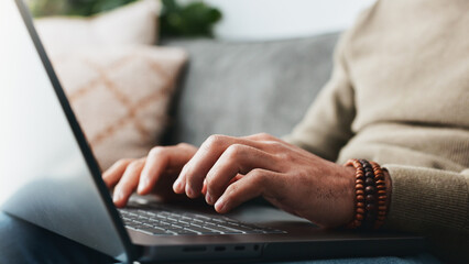 Laptop, typing and relax with hands of man on sofa for search, social media and blog post. Networking, email and update with closeup of person in living room at home for chat forum, digital or online