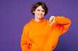 © ViDi Studio - Young sad unhappy dissatisfied displeased Caucasian woman she wear orange hoody casual clothes showing thumb down dislike gesture isolated on plain purple background studio portrait Lifestyle concept
