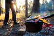 © Austockphoto - Camp oven over campfire cooking dinner - kids play nearby fire