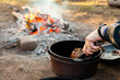 © Austockphoto - Cooking food in camp oven over campfire in winter