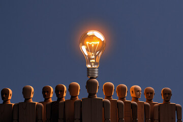 Poster - Illuminated lightbulb atop a wooden figure's head amongst a group of figures against a dark blue background. Symbolizing ideas, innovation, and leadership.