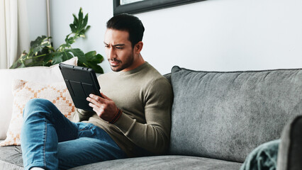 Fototapete - Tablet, reading and man on sofa in home with online blog, post or news article for politics. Digital technology, research and male person with social networking on media in living room at apartment.