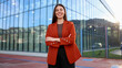 © PeopleVideos - Confident businesswoman smiling with crossed arms in modern business environment