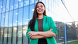 © PeopleVideos - Smiling businesswoman standing with arms crossed in front of modern office building