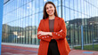 © PeopleVideos - Young businesswoman smiling with crossed arms in front of modern office building