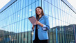 © PeopleVideos - Smiling businesswoman using tablet in front of modern office building
