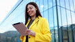 © PeopleVideos - Smiling businesswoman using digital tablet in front of modern office building