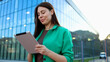 © PeopleVideos - Businesswoman using digital tablet in front of modern office building