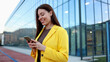 © PeopleVideos - Smiling businesswoman using smartphone in front of modern office building