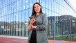 © PeopleVideos - Businesswoman using smartphone in front of modern office building